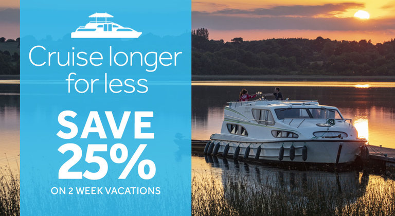 Cruise longer for less: 2 week discount. Image of a moored houseboat on a lake during a sunset in the background.